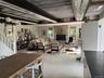 Dining space featuring stairs, a stone fireplace, finished concrete floors, and a wooden ceiling with exposed beams