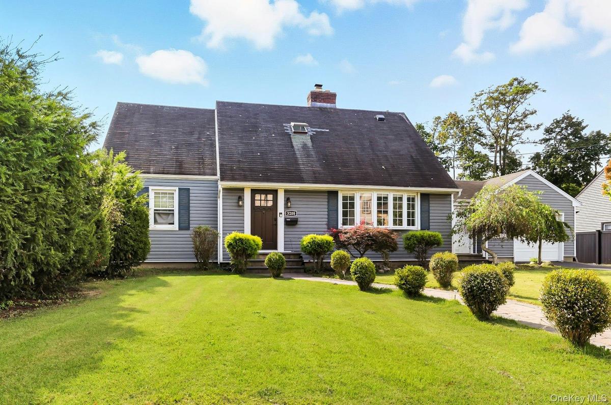 View of front of house with a front lawn, a chimney, roof with shingles, and entry steps