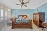 Primary bedroom with crown moldings, fluted, casings, and Plant blocks. Wall of windows with plantation shutters.