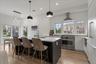 Kitchen featuring hanging light fixtures, appliances with stainless steel finishes, a breakfast bar, an island with sink, and extractor fan