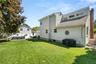 Expansive backyard featuring a manicured lawn, white privacy fencing, and a dedicated patio area
