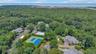 Expansive aerial perspective showcasing a residential community surrounded by dense tree cover