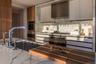 Kitchen featuring modern cabinets, wall chimney range hood, appliances with stainless steel finishes, backsplash, and a sink