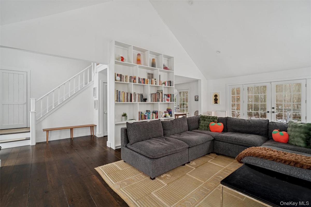 Living area with high vaulted ceiling, french doors, wood-type flooring, and stairway