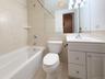 Full bath featuring tile walls, vanity, shower / bath combination, and light tile patterned flooring