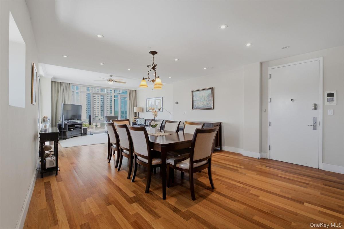 Open-concept living area featuring wood-finish flooring, recessed lighting, and a chandelier