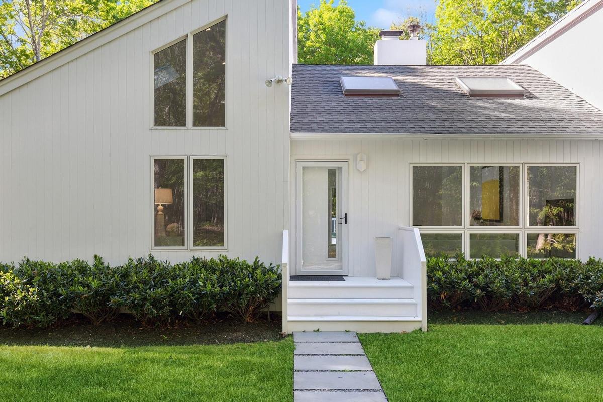 Mid-century home featuring roof with shingles, a front lawn, and a chimney