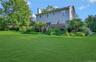Back of house featuring a chimney, a deck, and a lawn