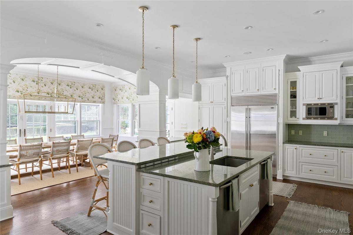 Kitchen with white cabinets, a kitchen island with sink, a sink, a kitchen bar, and built in appliances