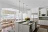 Kitchen with white cabinets, a kitchen island with sink, a sink, a kitchen bar, and built in appliances