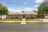 Brick exterior residence featuring a front lawn and paved walkway