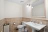 Half bath featuring wainscoting and tile walls