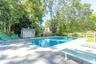 View of pool featuring a patio, view of wooded area, and a storage shed