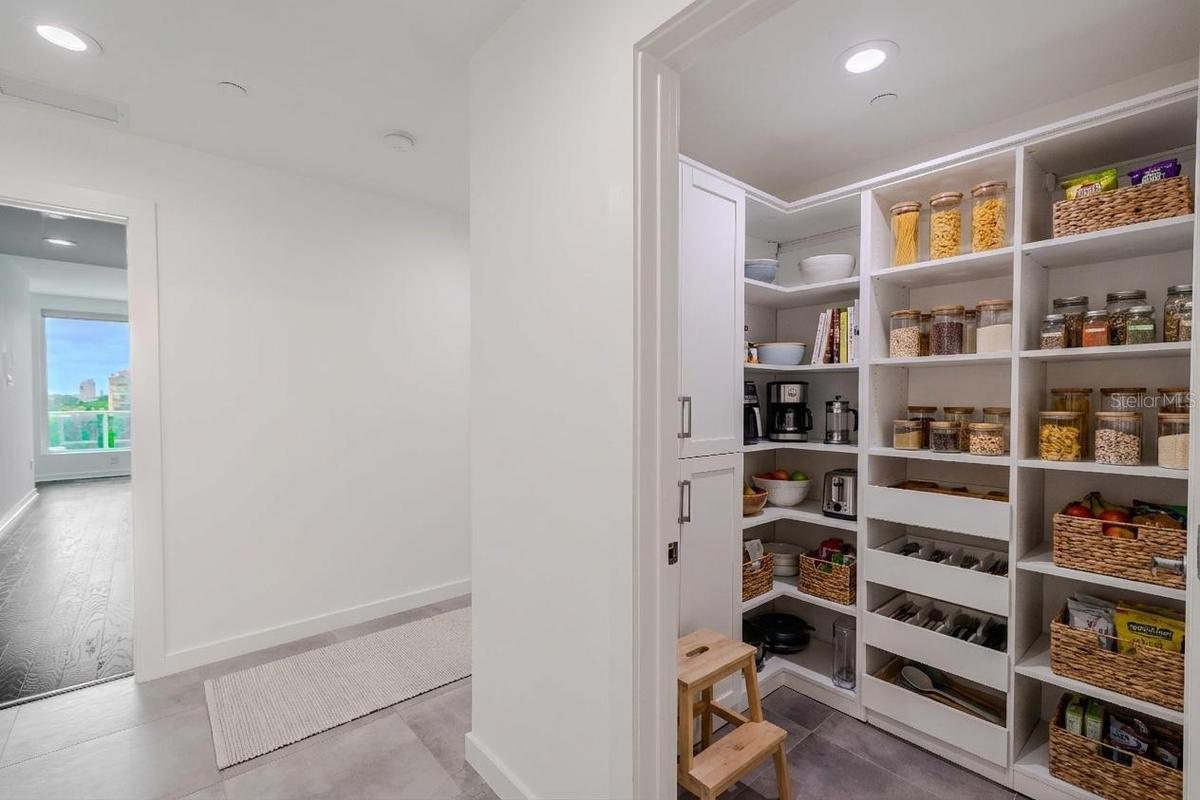 Spacious walk-in pantry with custom built-in shelving, ample storage, and pull-out drawers for easy organization. Clean white cabinetry and adjustable