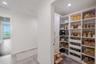 Spacious walk-in pantry with custom built-in shelving, ample storage, and pull-out drawers for easy organization. Clean white cabinetry and adjustable