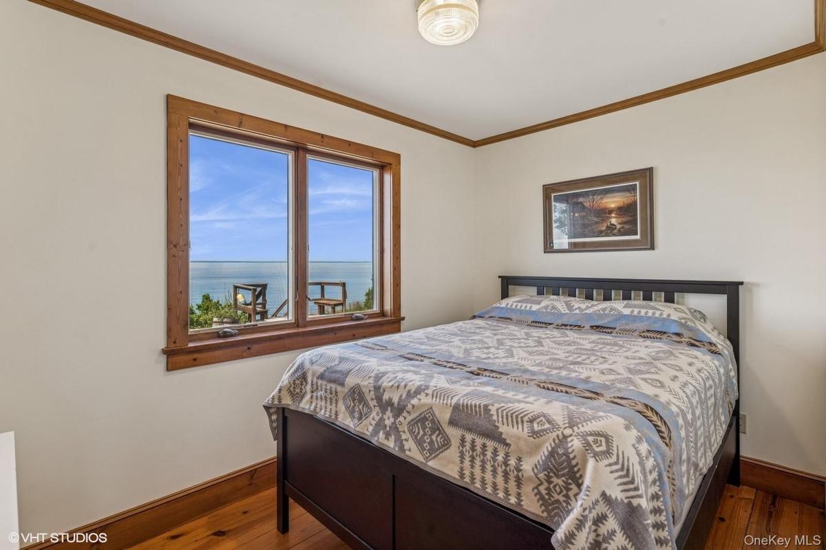 Bedroom with ornamental molding, a water view, and wood-type flooring