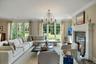 Living area featuring ornamental molding, a chandelier, a glass covered fireplace, and wood finished floors