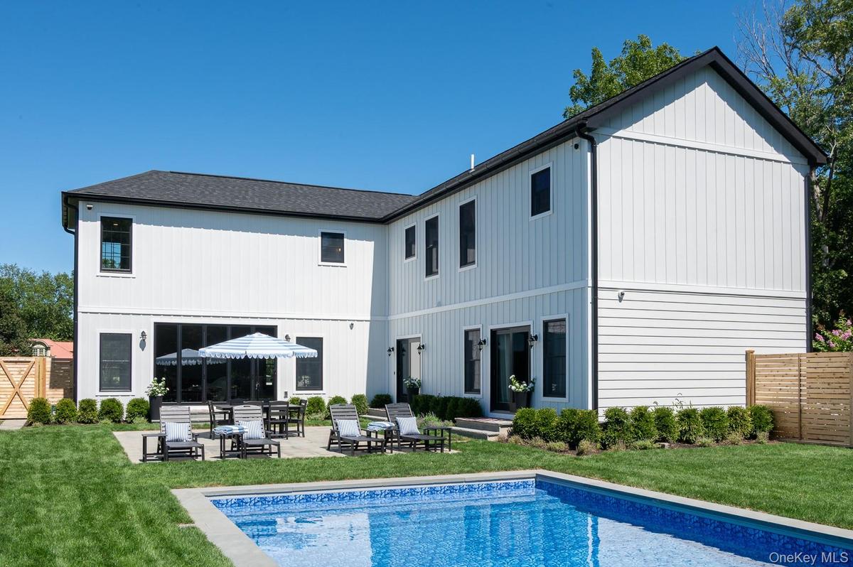 Back of property with a patio area, an outdoor pool, and a incredible sun.