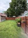 Expansive backyard featuring a privacy fence, mature trees, and a spacious lawn