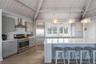 Kitchen featuring wood finished floors, stainless steel appliances, a sink, wall chimney range hood, and gray cabinets