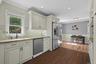 Kitchen featuring crown molding, dark wood-type flooring, stainless steel refrigerator with ice dispenser, light stone countertops