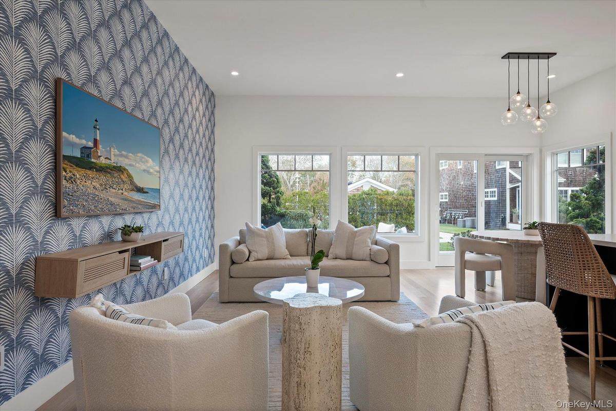 Living room with wallpapered walls, recessed lighting, an accent wall, wood finished floors, and a chandelier