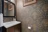 Stylish powder room featuring designer wall-paper and tasteful finishes.