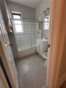 Bathroom featuring bath / shower combo with glass door, vanity, and light tile patterned flooring