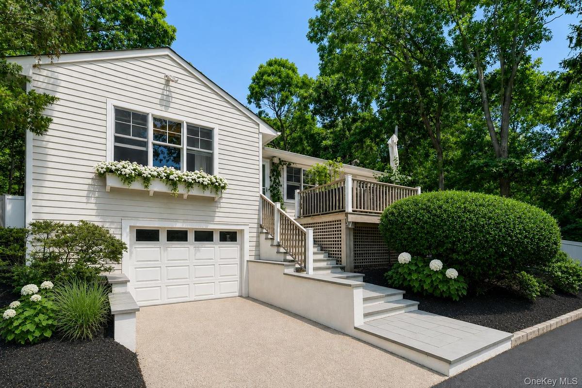 Coastal home with water view, garage, windows with box planters, spacious deck and yard