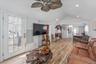Living area with arched walkways, light wood-style floors, ceiling fan, and hanging lights