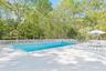 View of pool featuring view of scattered trees, a patio, and a deck
