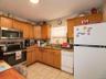 Kitchen featuring appliances with stainless steel finishes, light stone countertops, light tile patterned floors, and brown cabinets