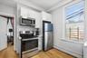 1st Floor Apartment kitchen features light-colored cabinets, stainless steel appliances, a geometric tile backsplash, and light wood flooring