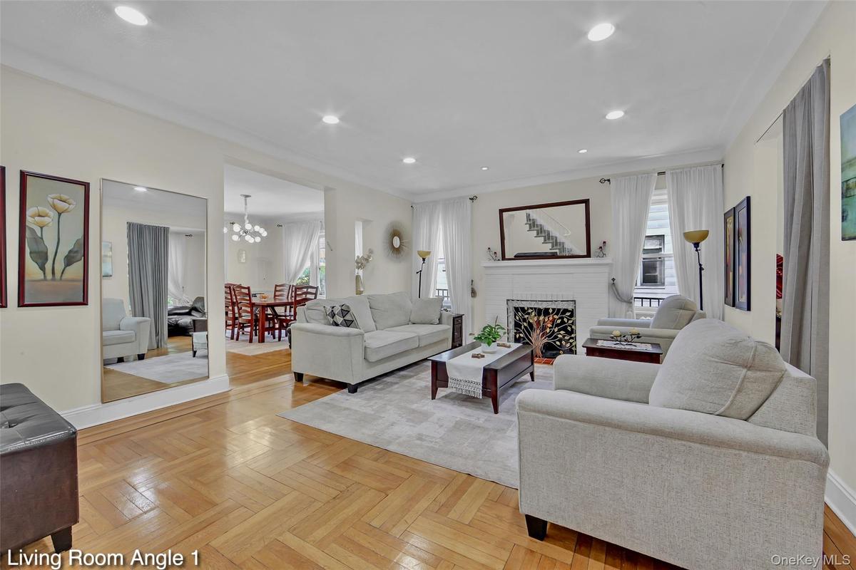 Living room featuring wood-finish herringbone flooring, recessed lighting, and a white brick fireplace with a decorative screen