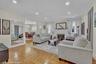 Living room featuring wood-finish herringbone flooring, recessed lighting, and a white brick fireplace with a decorative screen