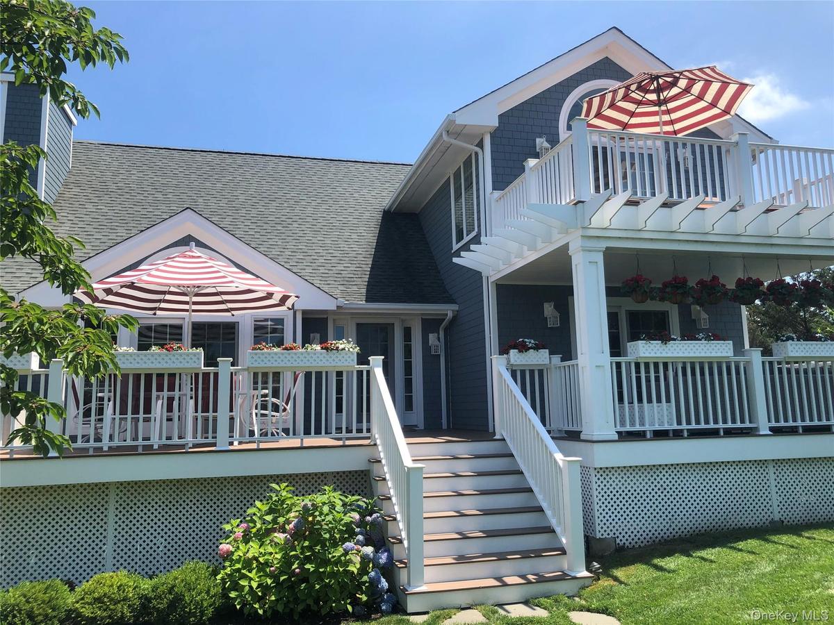 View of front of home with a shingled roof, a wooden deck, and stairway