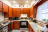 Kitchen with gas range oven, light tile patterned floors, light countertops, and black microwave