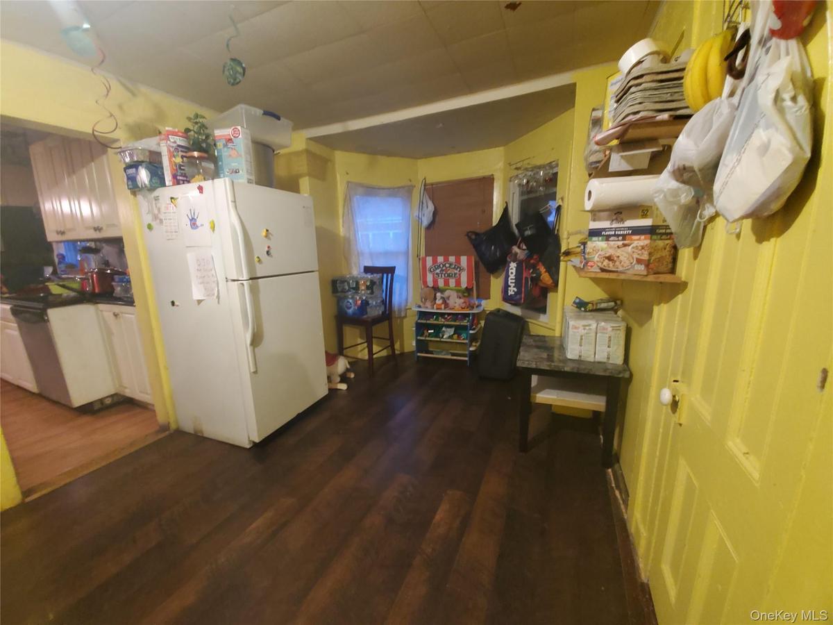 Kitchen with freestanding refrigerator, dark countertops, and dark wood-type flooring