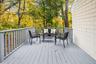 Freshly painted front porch surrounded by mature trees, offering a peaceful spot to enjoy morning coffee or unwind outdoors.