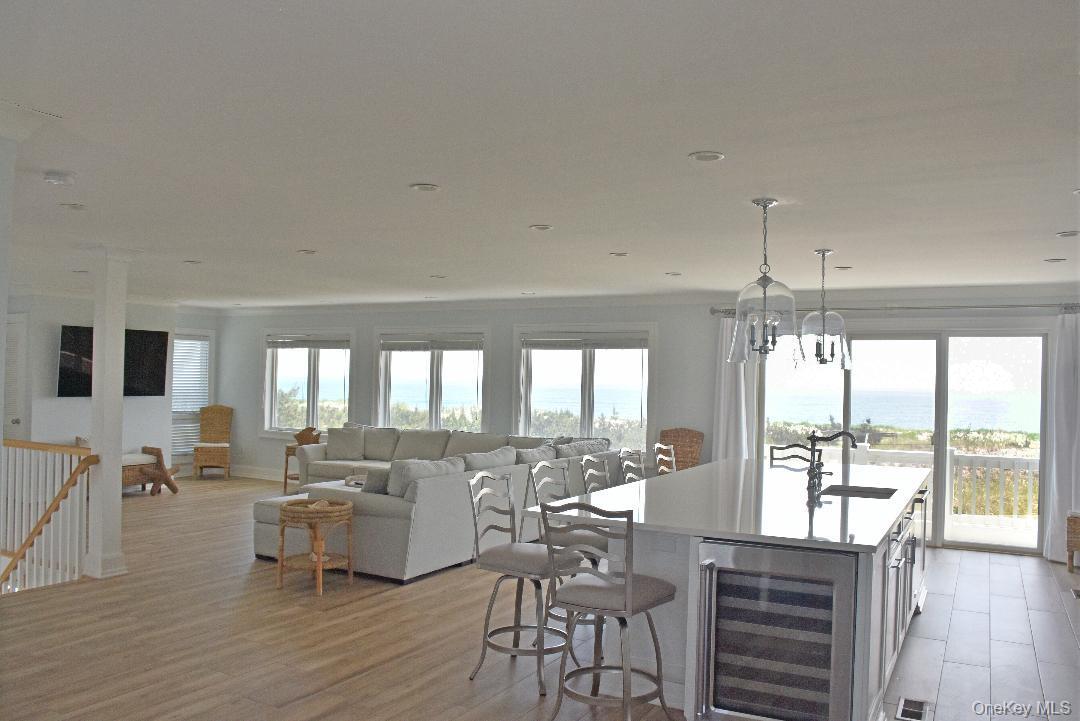 Kitchen featuring a center island with sink, a chandelier, light hardwood / wood-style floors, wine cooler, and hanging light fixtures