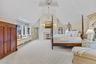 Master bedroom featuring light colored carpet, a chandelier, a fireplace, and beamed ceiling.