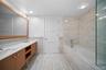 Bathroom featuring tile walls, double vanity, a garden tub, and a wainscoted wall