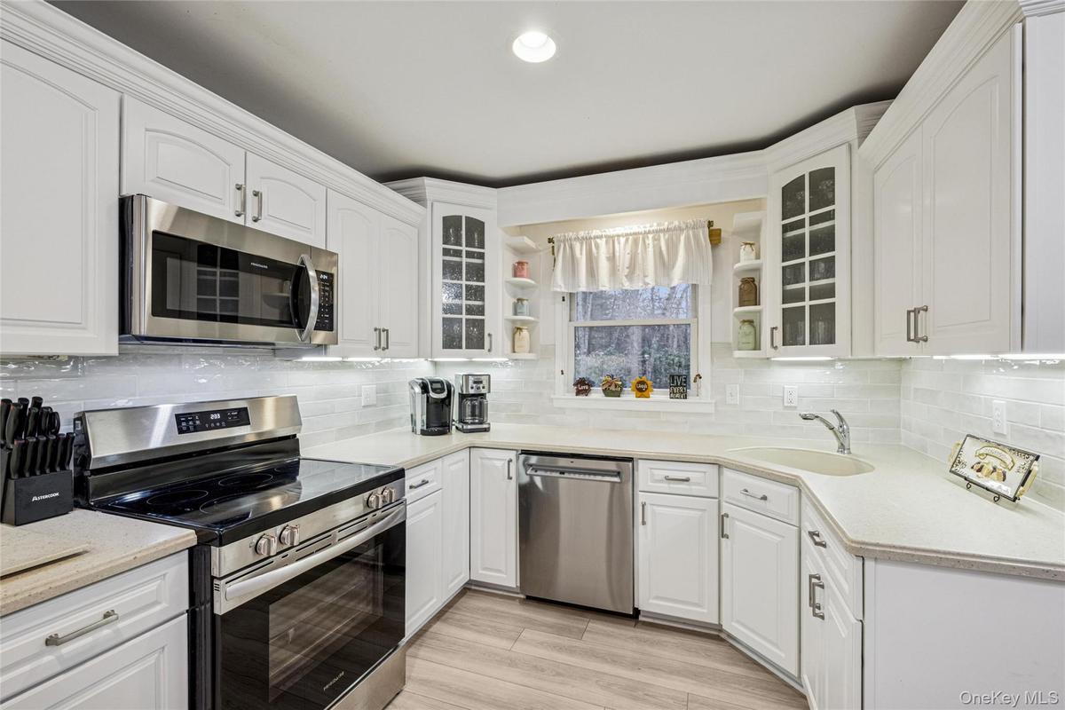 Kitchen featuring stainless steel appliances, open shelves, glass insert cabinets, white cabinets, and recessed lighting
