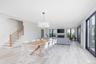 Dining space with light wood-style flooring, a glass covered fireplace, stairs, and baseboards