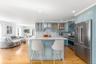 Kitchen with premium appliances, wall chimney exhaust hood, a kitchen breakfast bar, decorative backsplash, and recessed lighting