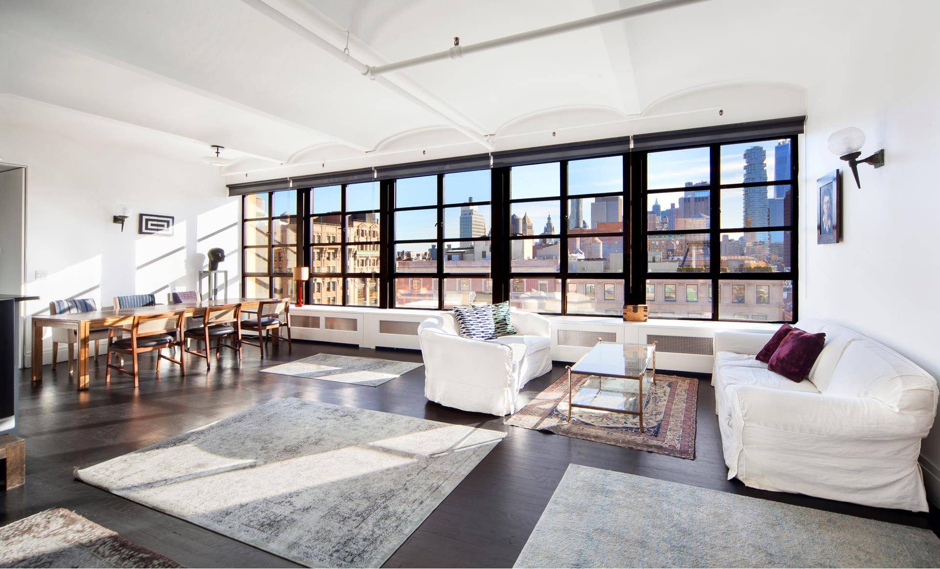 Extraordinary, sunny and gracious characterize this top floor iconic SoHo loft dominated by exceptional views of downtown Manhattan seen through a row of beautifully framed casement windows.