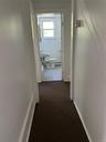 Hallway featuring baseboard heating, sink, and dark carpet