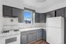 Kitchen with white appliances, gray cabinetry, light countertops, dark wood-style floors, and tasteful backsplash