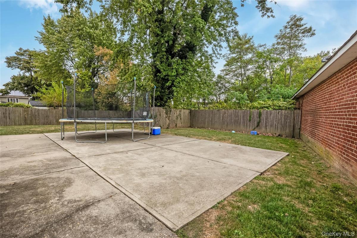 Fenced backyard with a trampoline and a patio area