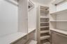 Walk-in closet featuring white shelving systems, multiple hanging rods, and adjustable shelves